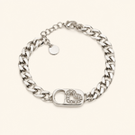 Bracelet Gizem argenté à mailles gourmette avec fermoir cœur serti de zirconiums sur fond beige clair minimaliste