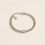 Bracelet Gena argenté style gourmette avec pierre rectangulaire lumineuse sur fond crème minimaliste