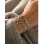 Bracelet Gena argenté style gourmette avec pierre facettée lumineuse porté en accumulation sur un poignet féminin