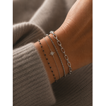 Bracelet Gaya argenté à mailles géométriques porté sur un poignet féminin avec accumulation de bracelets fins argentés