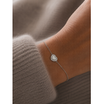 Bracelet Noa argenté avec cœur blanc nacré et zirconiums porté sur un poignet féminin en maille douce beige taupe