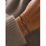 Bracelet Mona argenté avec petits zirconiums lumineux porté sur un poignet féminin en maille douce beige taupe