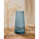Pichet en verre bullé bleu artisanal posé sur une table en bois dans une ambiance décoration naturelle et chaleureuse