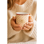 Femme tenant un mug Love More en porcelaine rayures beige rosé dans une ambiance cosy et chaleureuse