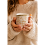 Femme tenant un mug Coffee en porcelaine à pois terracotta dans une ambiance cosy et chaleureuse