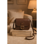 Sac bandoulière marron Amy en similicuir lisse posé sur des livres dans un intérieur cosy aux tons crème et caramel