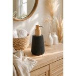 Distributeur à savon noir texturé avec pompe en bois naturel posé sur un meuble de salle de bain minimaliste en bois clair dans une ambiance chaleureuse et élégante style spa slow living