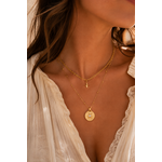 Femme portant le collier Patti double chaîne dorée avec pendentif astral et pierre blanche dans une ambiance bohème chic élégante et lumineuse