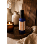 Brume de maison senteur fleur d’oranger en verre bleu fumé posée sur un plateau en bois foncé dans une décoration chaleureuse et raffinée slow living