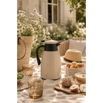 Thermos isotherme beige naturel dans une ambiance pique-nique élégante au jardin avec pâquerettes, textile en lin, verres ambrés et décoration slow living chaleureuse
