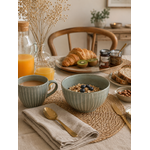 Bol en grès vert sauge à rayures blanches présenté sur une table de petit-déjeuner chaleureuse et conviviale