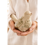 Figurine oiseau décorative en grès émaillé à motif feuillage vert tenue dans les mains pour montrer sa taille réelle dans une ambiance naturelle et chaleureuse.