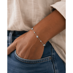 Bracelet Ellie argenté en acier inoxydable porté à la main dans une poche de jean, bijou fin avec fleurs et cristaux dans un style naturel et élégant.