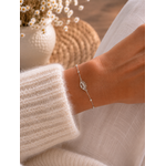 Bracelet Lorine argenté en acier inoxydable porté au poignet, avec œil protecteur ajouré et perles blanches, dans une ambiance naturelle et élégante.