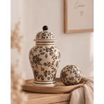 Vase Tibor en grès écru à motifs floraux noirs avec son couvercle et sa boule décorative assortie sur un plateau en bois.