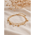 Bracelet Lilo doré double chaîne avec pampilles dorées et petites perles blanches porté dans une ambiance élégante et chaleureuse