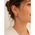 Boucles d’oreilles Cassie violettes en résine portées avec anneau doré et ambiance douce