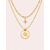 Collier Patti double chaîne dorée avec pendentif astral et pierre blanche sur fond rose poudré minimaliste