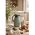 Thermos isotherme vert sauge sur table basse en bois clair dans un intérieur cosy avec pâquerettes naturelles, tasse en céramique et ambiance slow living élégante
