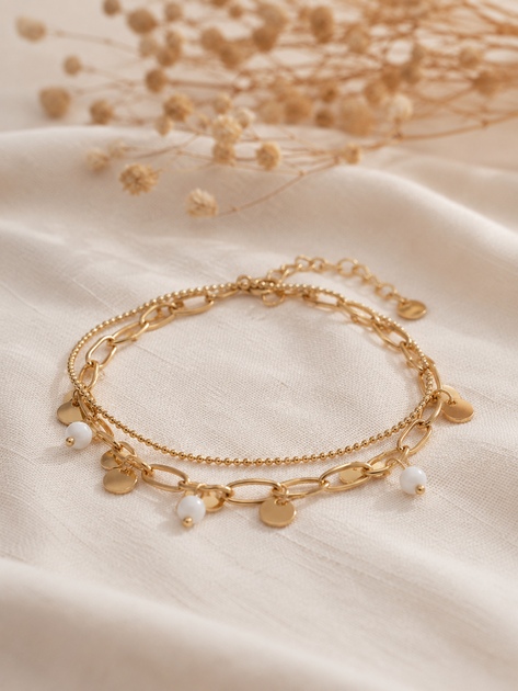 Bracelet Lilo doré double chaîne avec pampilles dorées et petites perles blanches porté dans une ambiance élégante et chaleureuse