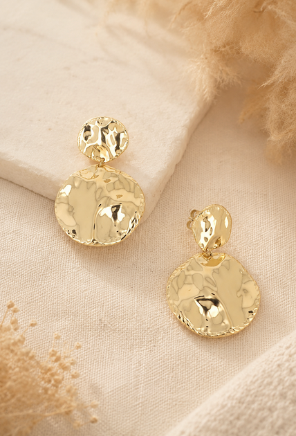 Boucles d’oreilles Astrid dorées en acier inoxydable sur fond beige doux et chaleureux