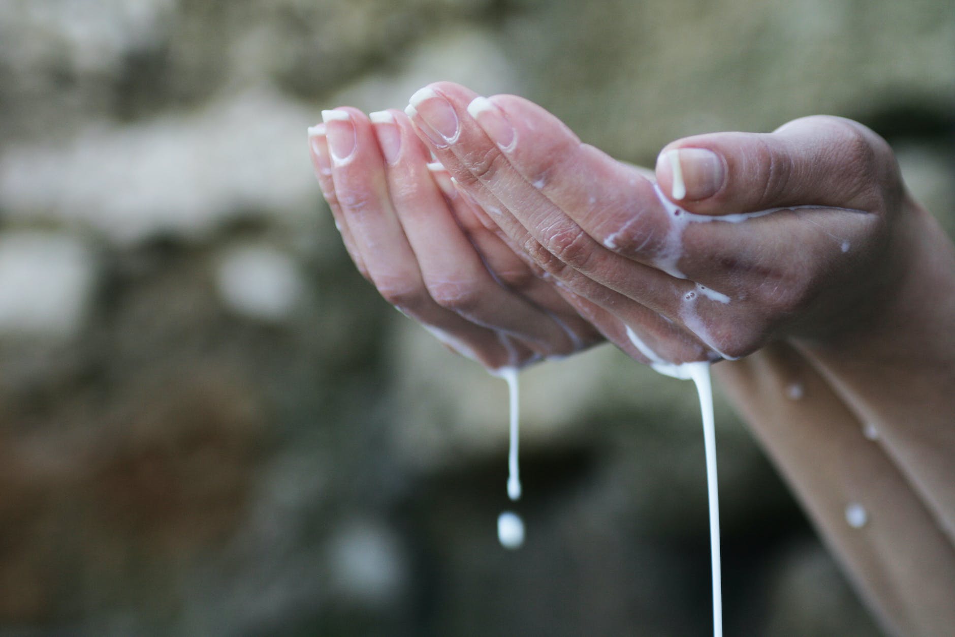 les mains de la personne couvertes de liquide blanc