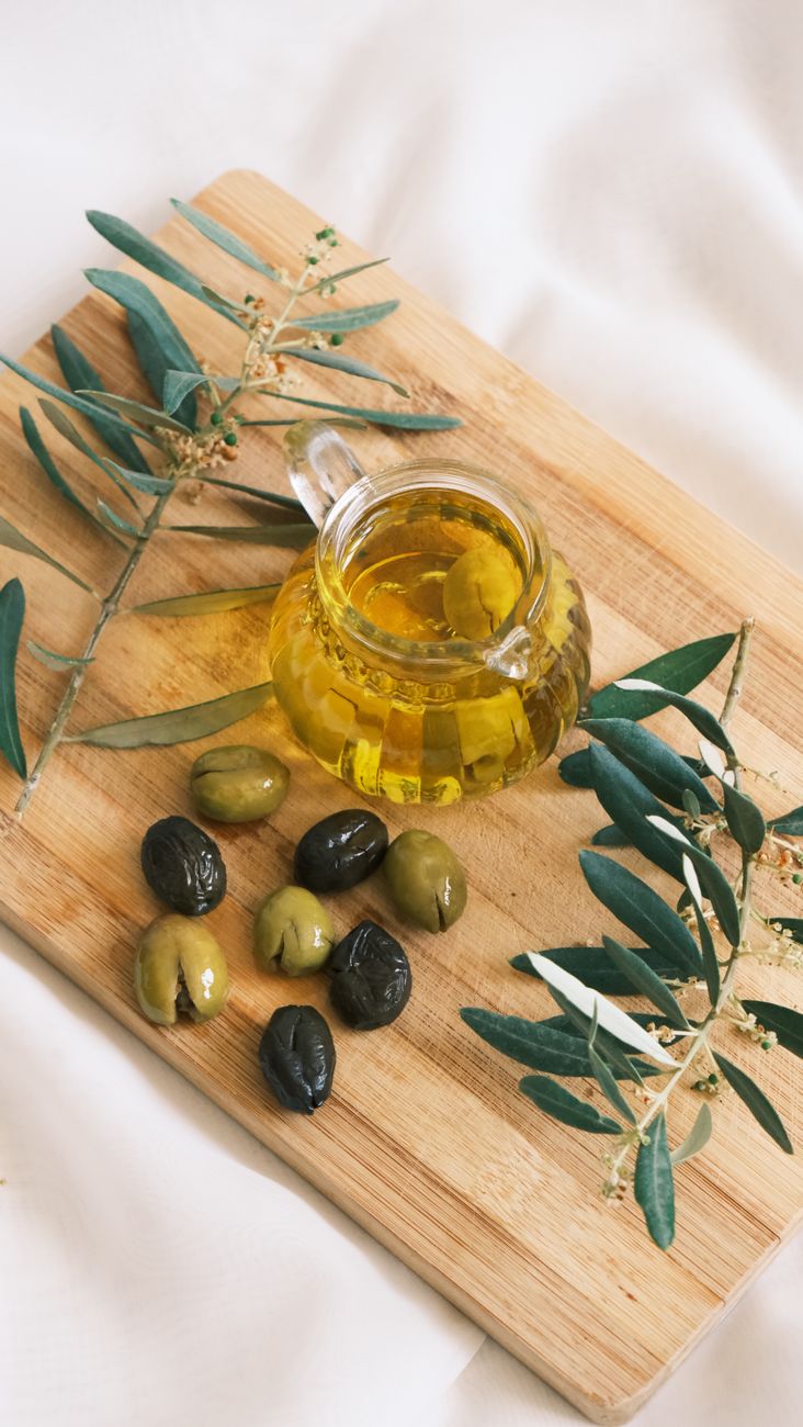 mise en scene conviviale avec des olives et de l huile d olive sur une planche en bois avec des branches d olivier
