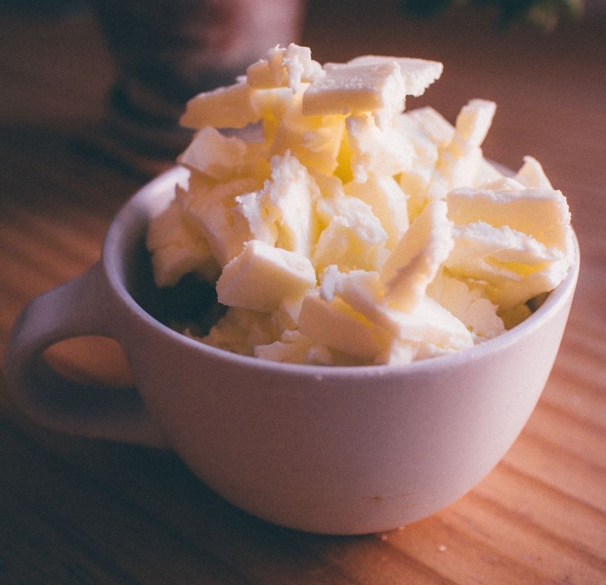 une pile de rouleaux de beurre empiles dans un mug en ceramique blanche sur une table en bois