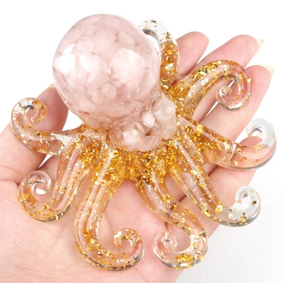 pieuvre d'ornement en résine pailletée et quartz rose posée sur une main