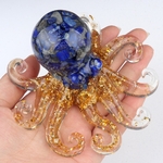 pieuvre d'ornement en résine pailletée et lapis lazuli posée sur une main