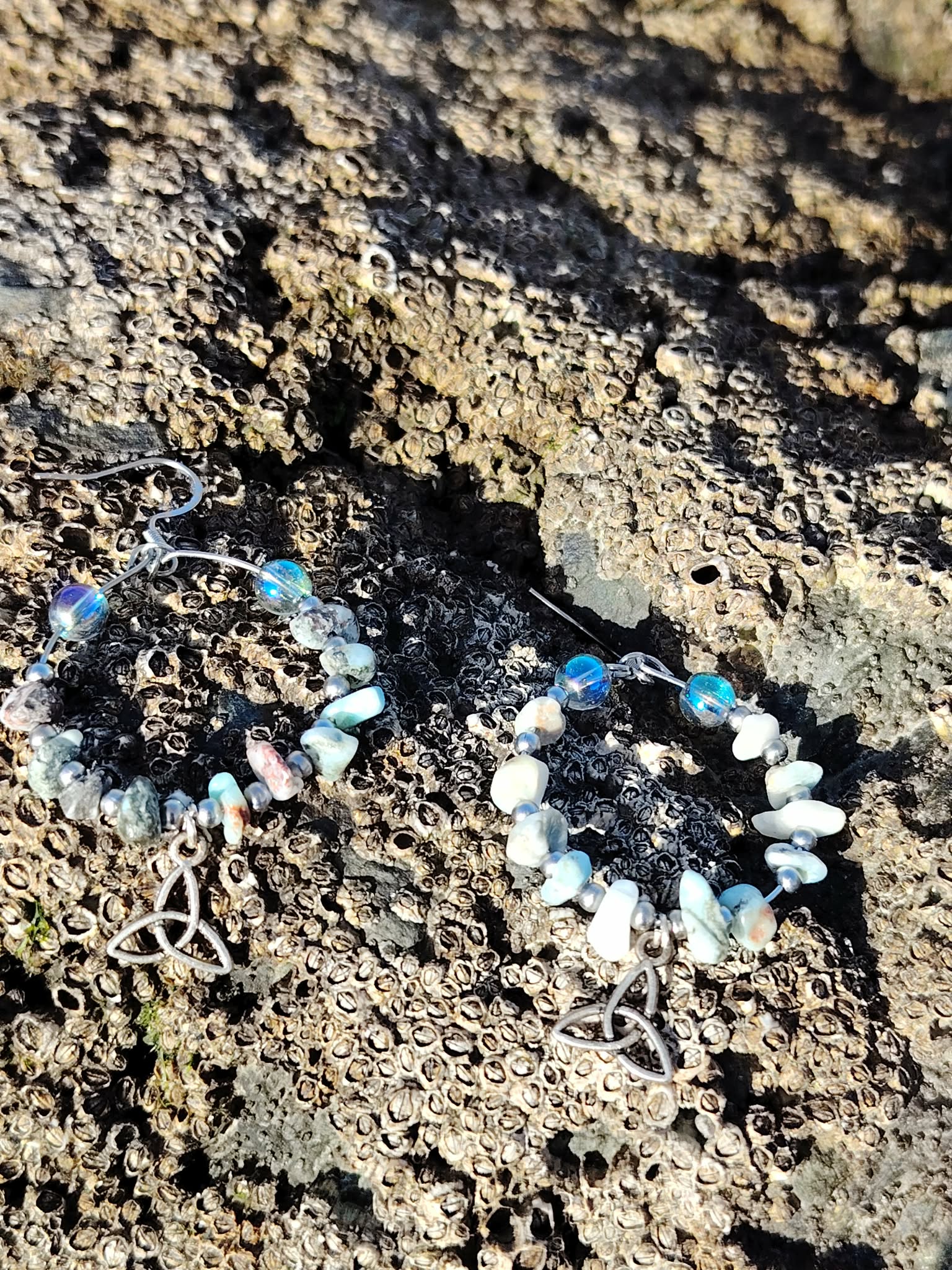 Boucles d’oreilles Magic Gaïa en larimar et aqua aura posées sur roche granitique bretonne texturée, perles bleu ciel et blanches en cercle, ambiance naturelle, évoquant douceur, intuition et équilibre émotionnel