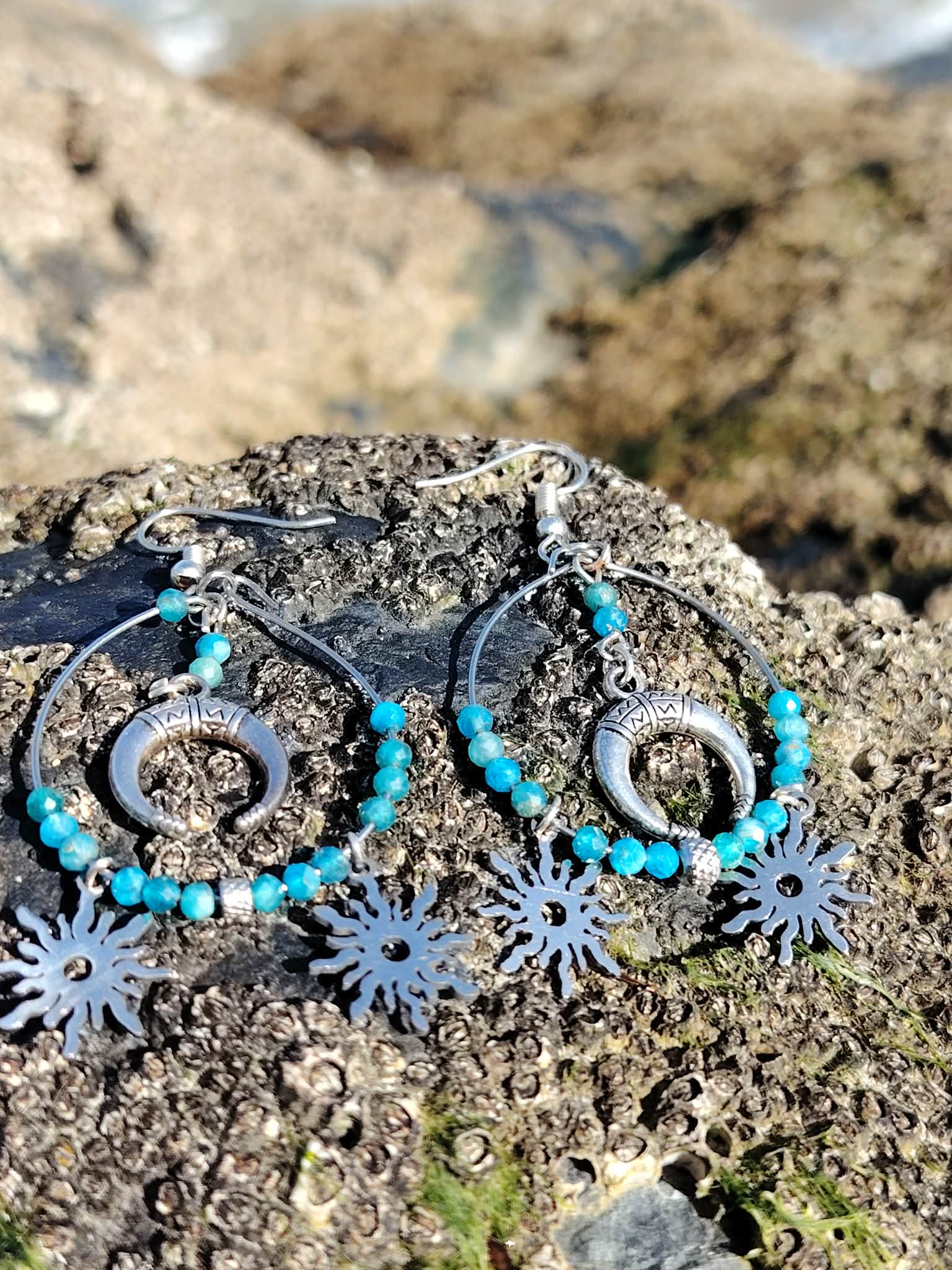 Boucles d’oreilles Atlante en apatite, création Magic Gaïa, photographiées sur roche en bord de mer en Bretagne, pour une énergie d’apaisement et de communication.