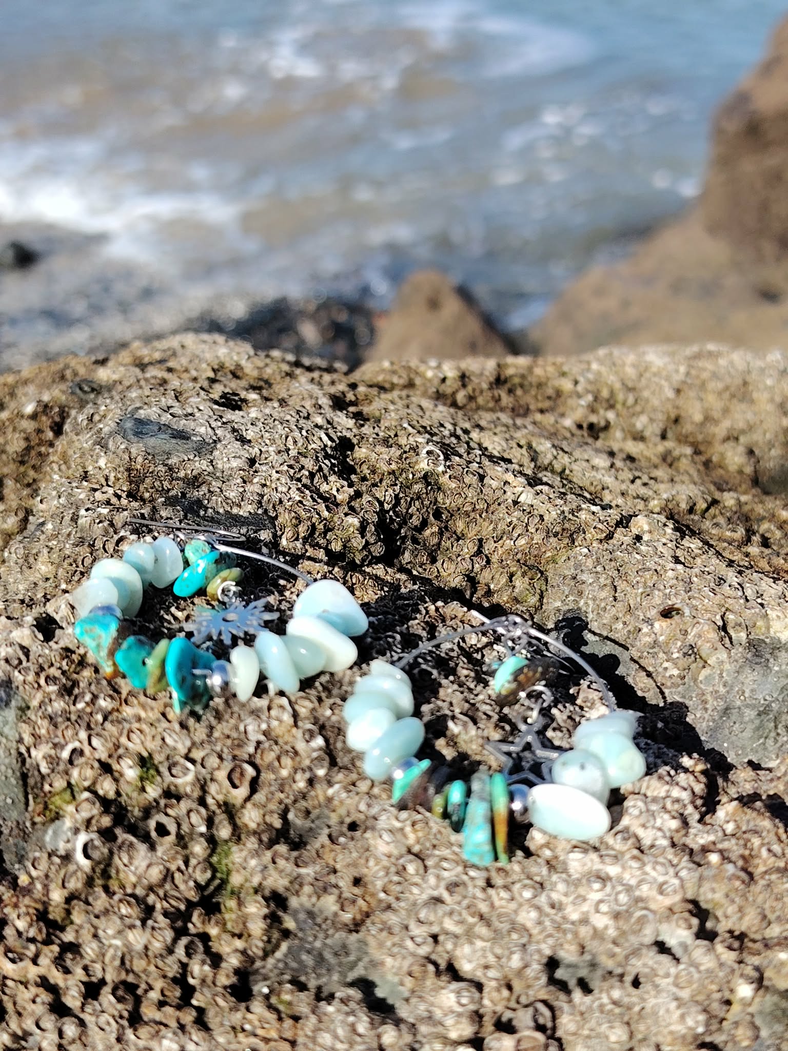 Boucles d’oreilles Ombre et Lumière, création Magic Gaïa, perles turquoise et blanches sur rocher breton face aux vagues, pour apaisement, confiance et clarté.
