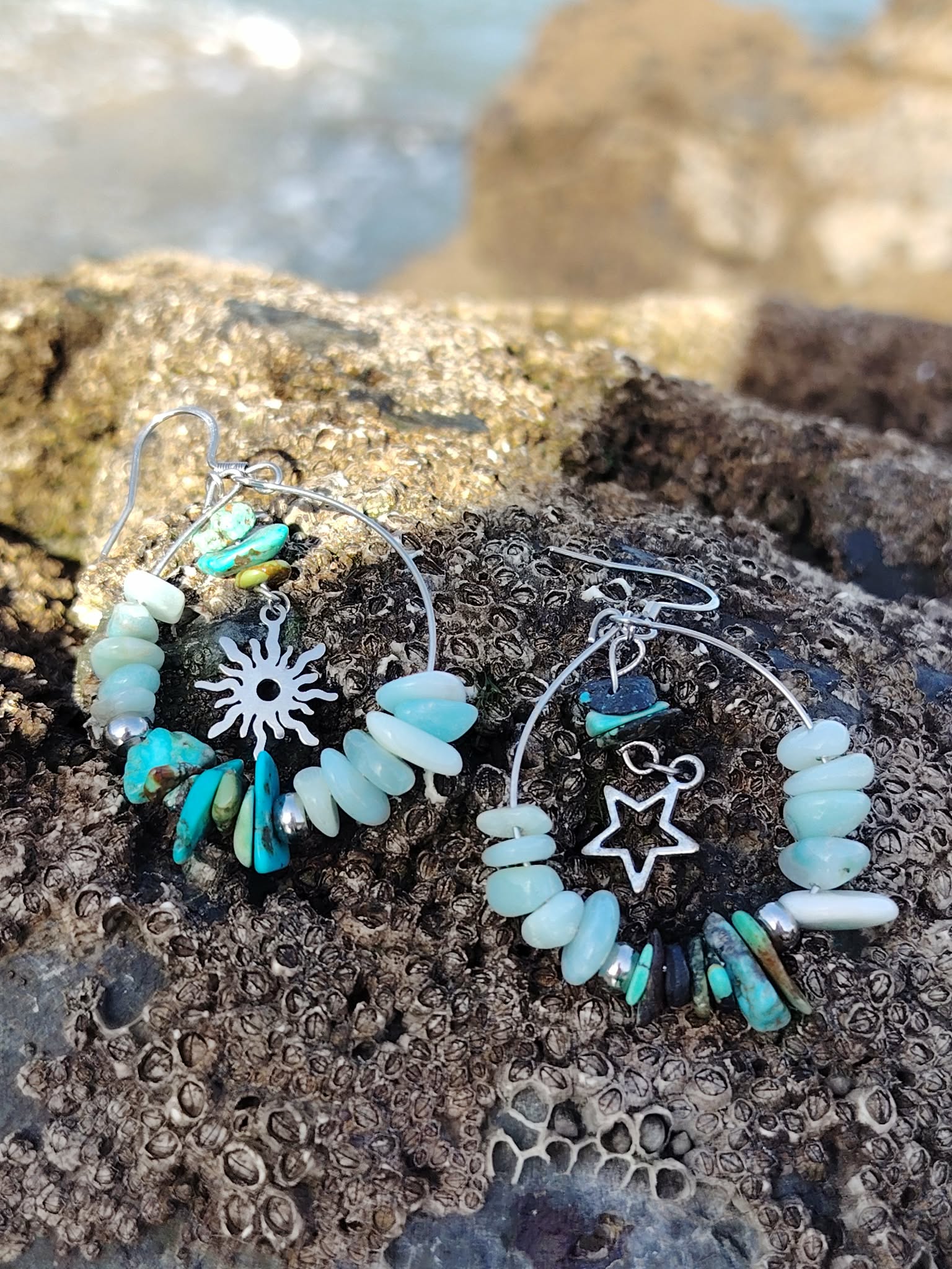 Boucles d’oreilles Ombre et Lumière, création Magic Gaïa, perles turquoise et blanches avec breloques étoile et soleil, sur rocher en Bretagne, pour apaisement et harmonie.