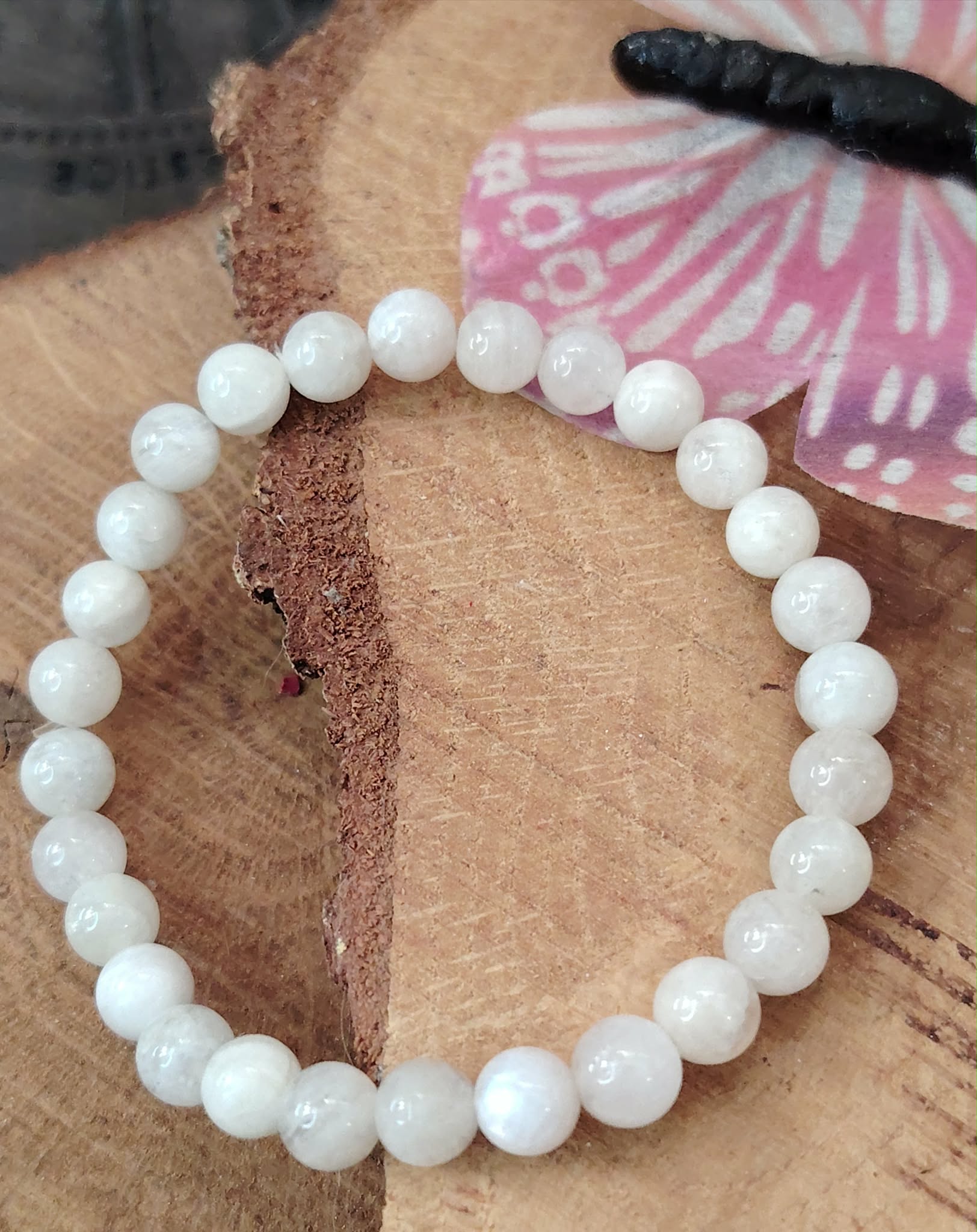 Bracelet péristérite 6 mm pierre de lune arc-en-ciel sur rondin de bois avec papillon rose, clarté intérieure et douceur.