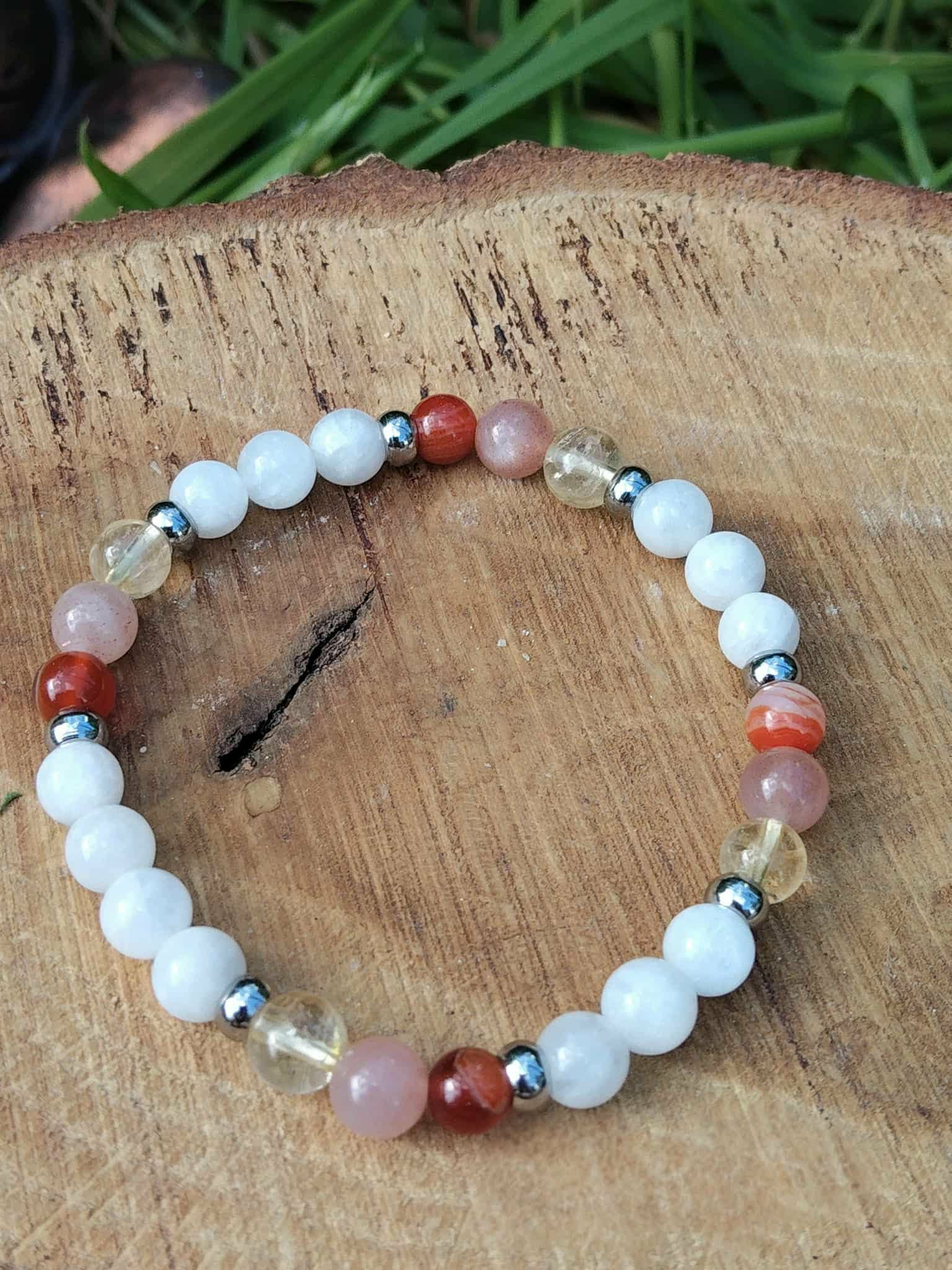 Bracelet PMA 6 mm en péristérite, pierre de soleil et cornaline, sur rondin de bois brut avec herbes vertes; douceur, élan et confiance.