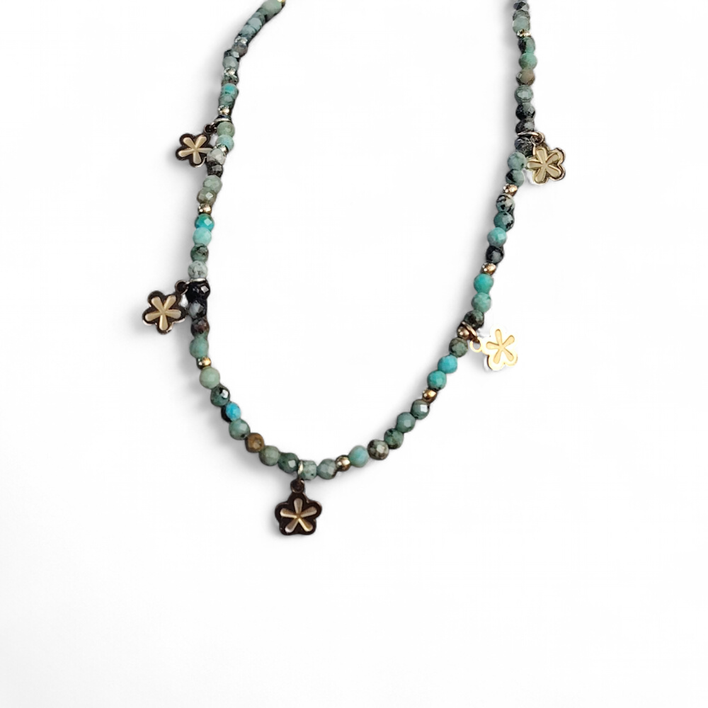 Collier doré vert africain facetté sur fond blanc, pendentifs fleur et acier inoxydable pour une allure lumineuse et délicate