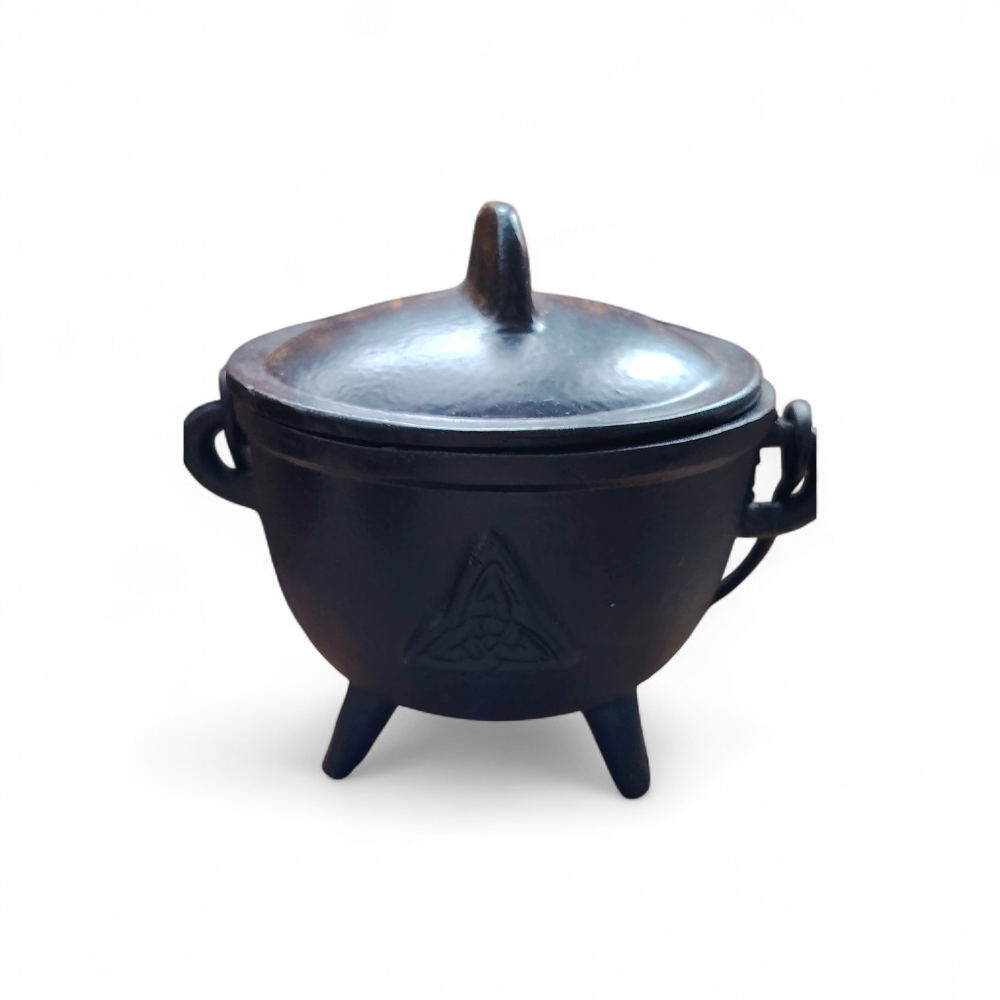 Petit chaudron en fonte noire avec couvercle arrondi et trois pieds stables, objet rituel détouré sur fond blanc.