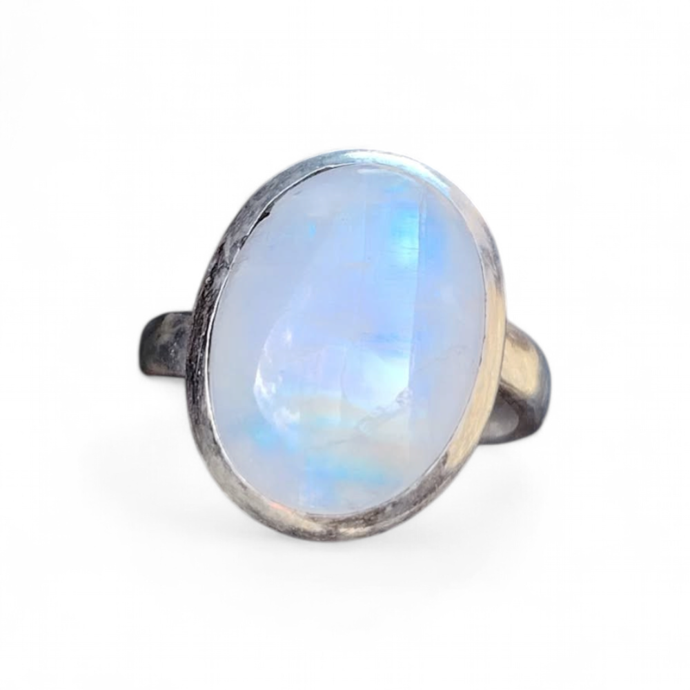 Bague réglable en argent 925 sertie d’une péristérite ovale (pierre de lune arc-en-ciel) sur fond blanc, reflets bleutés, intention douceur, apaisement et intuition.