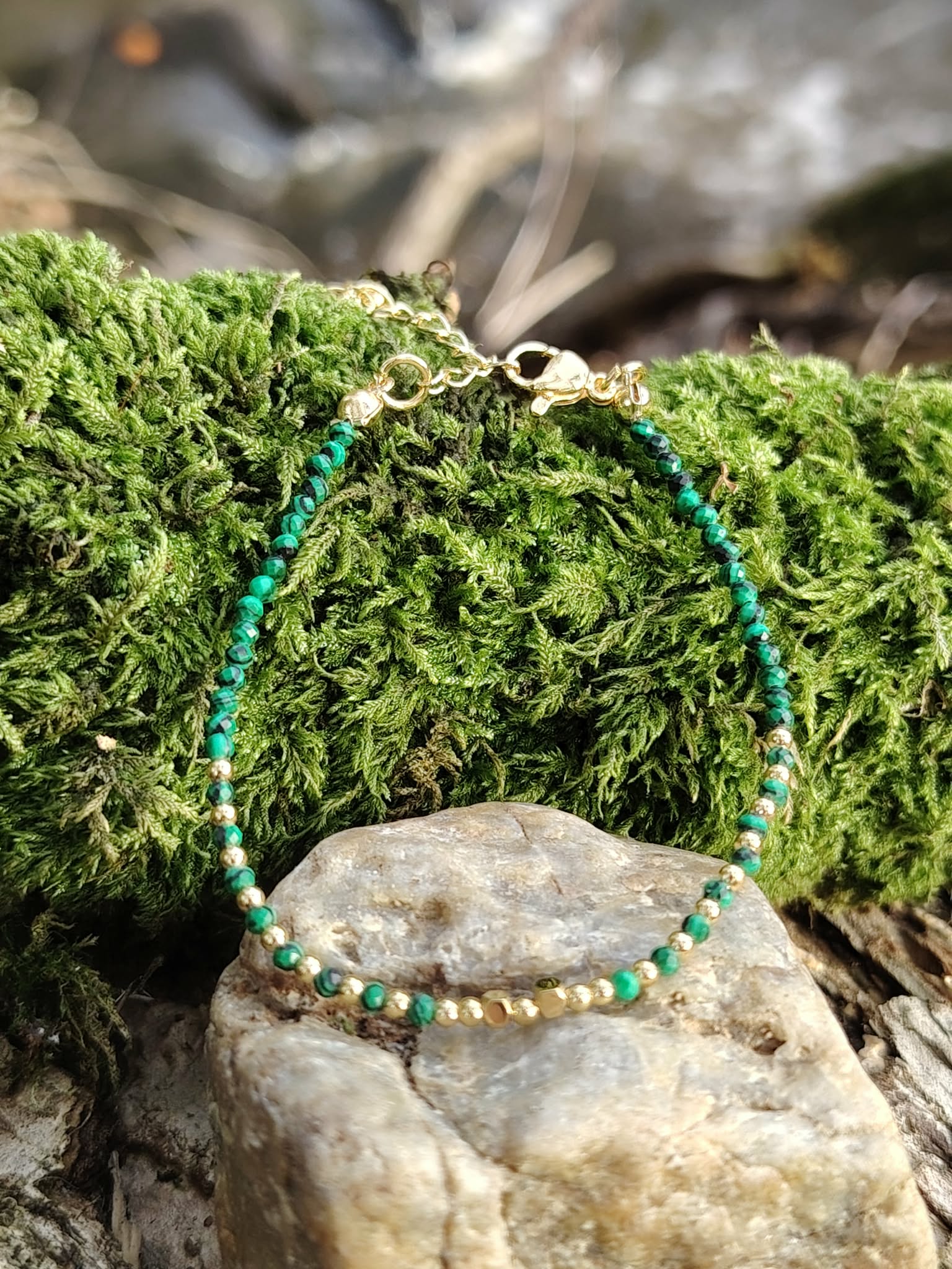 Bracelet malachite facettée 2 mm et cuivre plaqué or sur pierre claire devant mousse en forêt, ambiance nature et vert intense