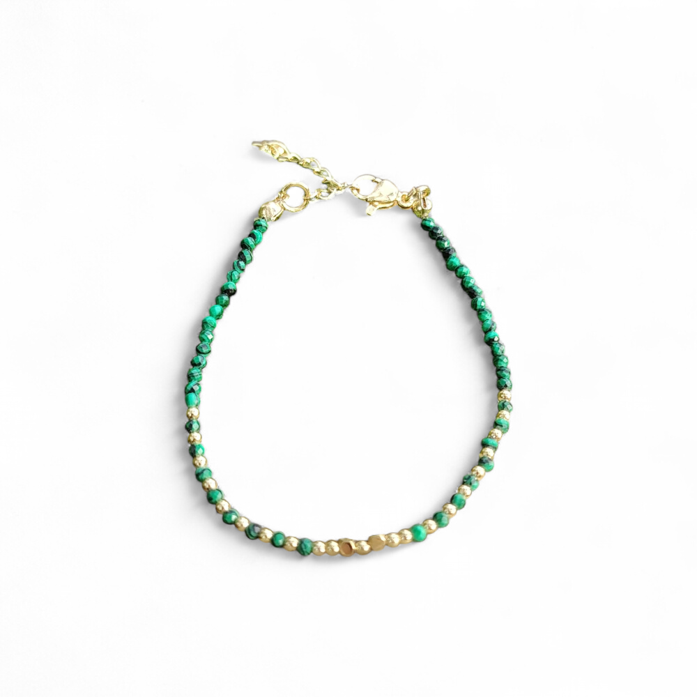 Bracelet fin en malachite facettée 2 mm sur fond blanc, cuivre plaqué or, forme ovale avec fermoir et vert profond lumineux.
