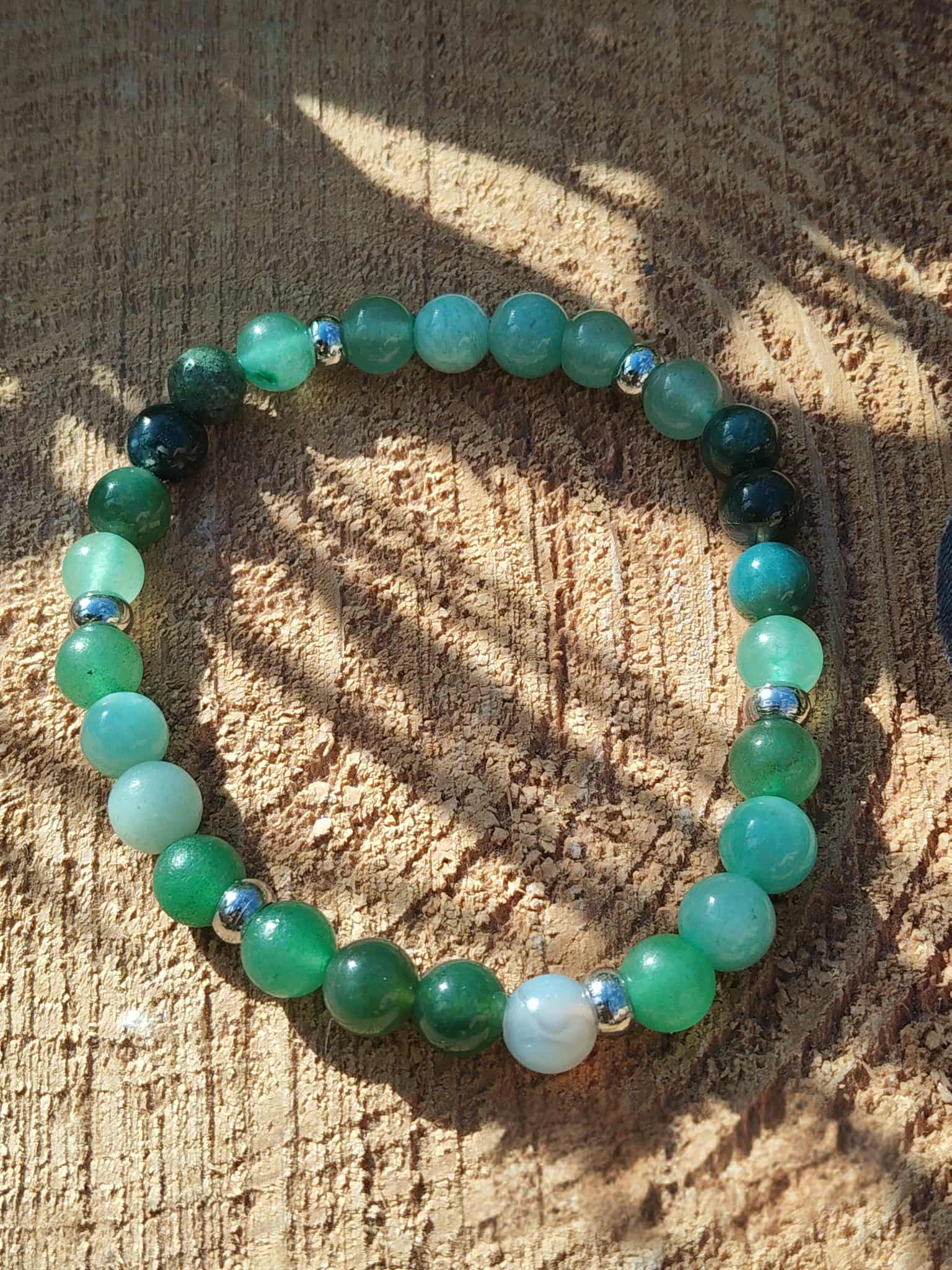 Bracelet Psoriasis 6 mm sur bois clair au soleil, perles vert d’eau et vertes avec intercalaires argentés pour ancrage doux et respiration plus paisible