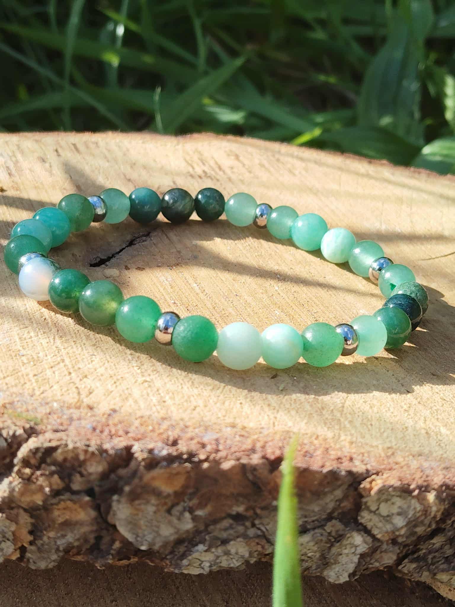 Bracelet Psoriasis 6 mm sur tranche de bois au soleil avec herbe en fond, amazonite, agate mousse et aventurine verte pour confiance douce et harmonie intérieure