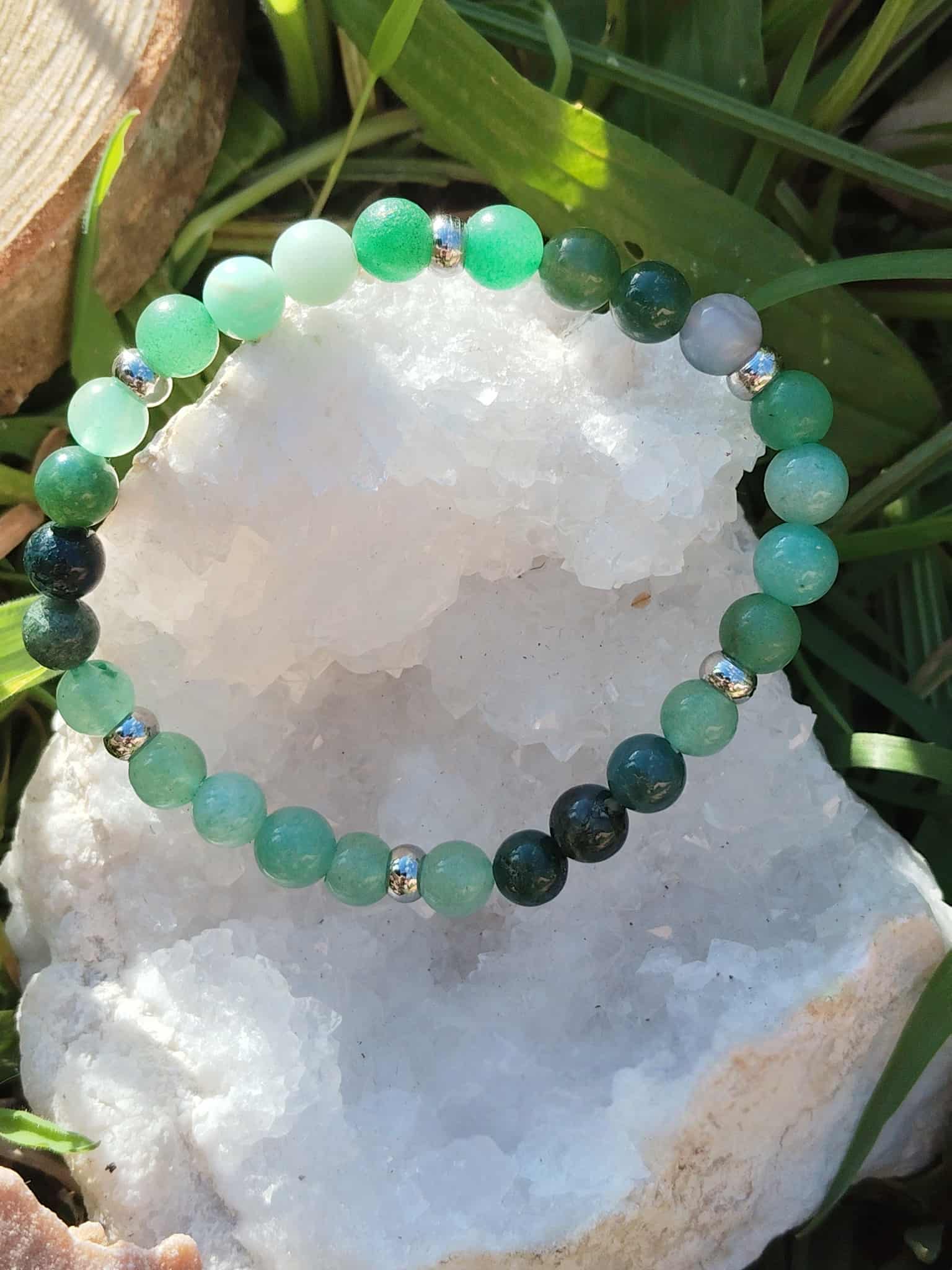 Bracelet Psoriasis 6 mm posé sur géode de quartz blanc dans l’herbe, amazonite, agate mousse et aventurine verte pour relâchement émotionnel et stabilité du ressenti