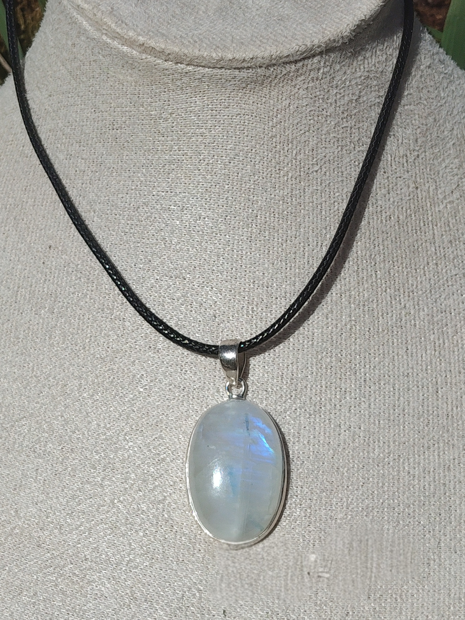 Pendentif labradorite blanche aux reflets bleus serti argent 925 sur cordon noir, présenté sur buste beige, pierre naturelle associée à l’apaisement, à l’intuition et à l’équilibre intérieur.