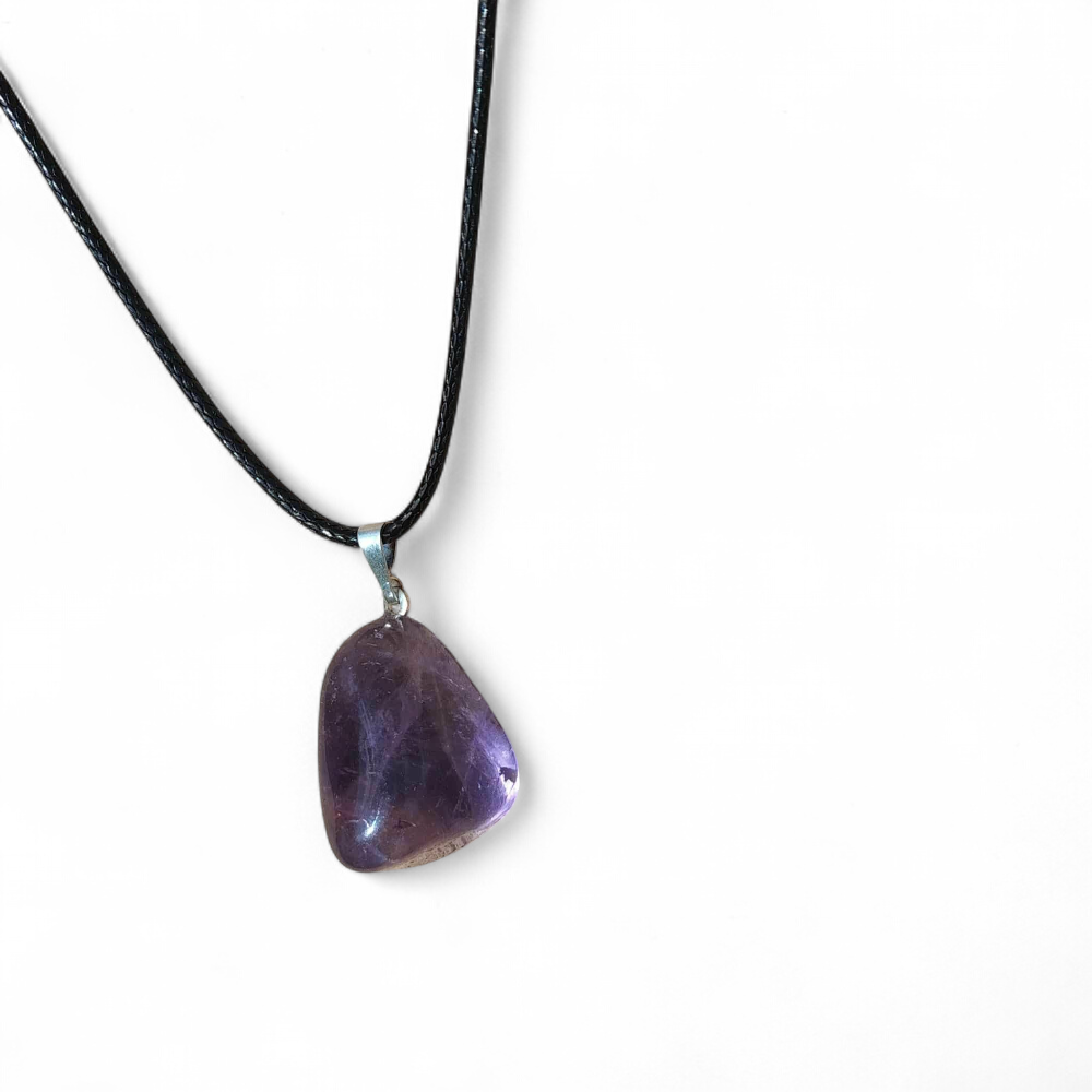 Pendentif en amétrine violette sur cordon noir, présenté sur fond blanc épuré, pierre naturelle reliée à la concentration, à la sérénité et à la lucidité intérieure.
