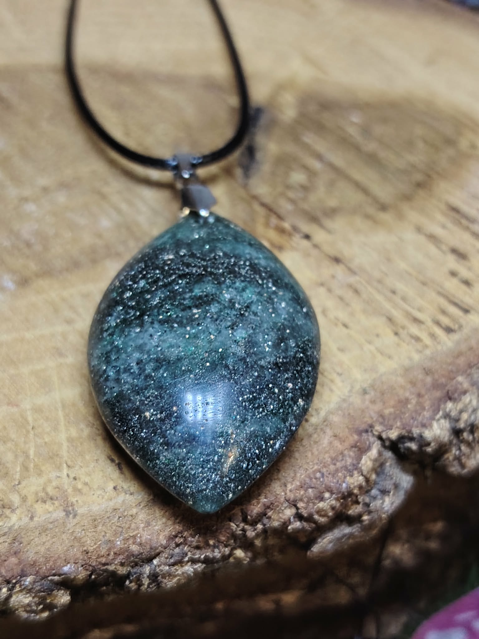 Pendentif en fuchsite avec inclusion de marcassite présenté sur vieux livre, dans une atmosphère douce et spirituelle évoquant harmonie, recentrage et sérénité.