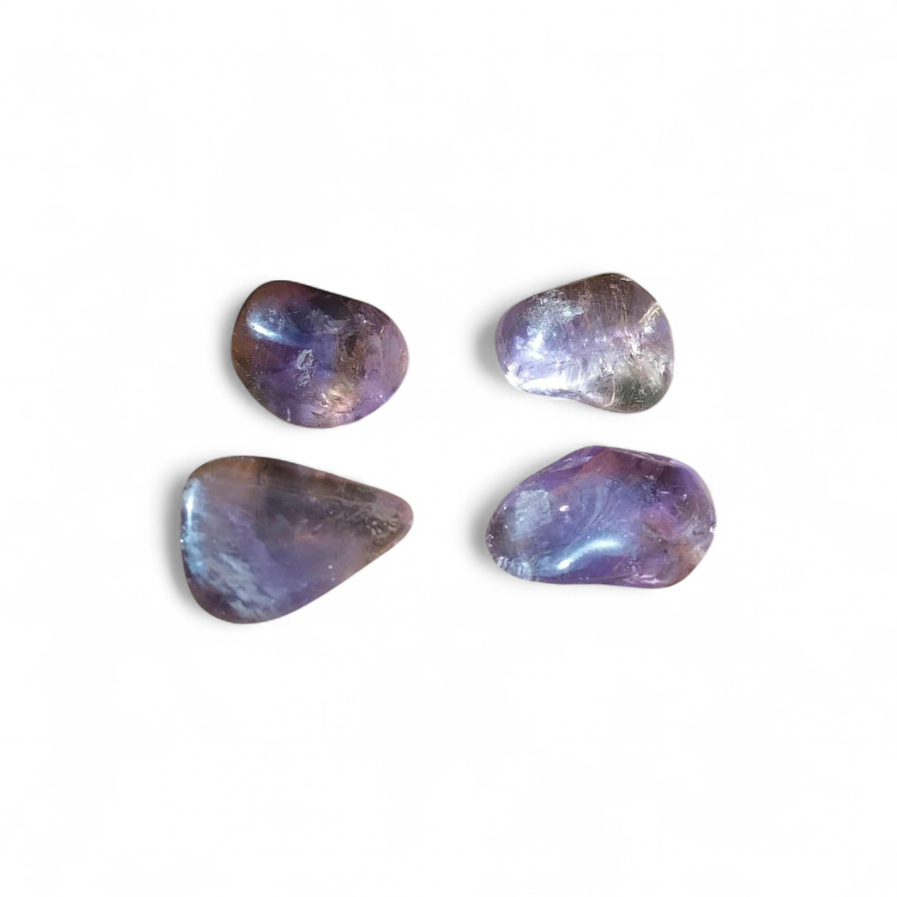 Quatre pierres roulées d’amétrine aux reflets violets et dorés sur fond blanc, pierres naturelles reliées à la lucidité, au calme du mental et à l’harmonie émotionnelle.