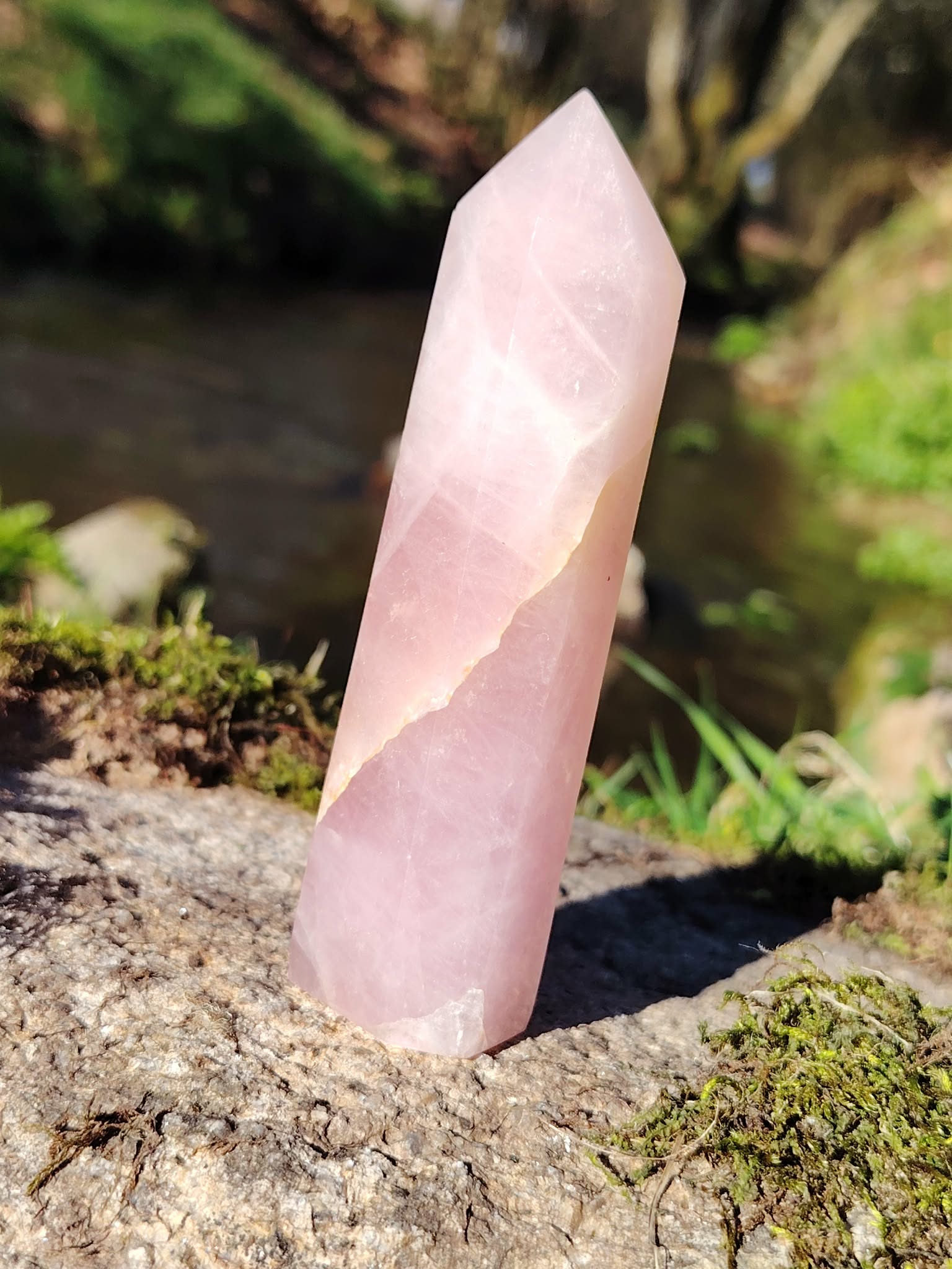 Pointe de quartz rose facettée dressée sur granit et mousse en Bretagne, près d’un ruisseau, pour apaiser le cœur, adoucir les émotions et encourager l’amour de soi.
