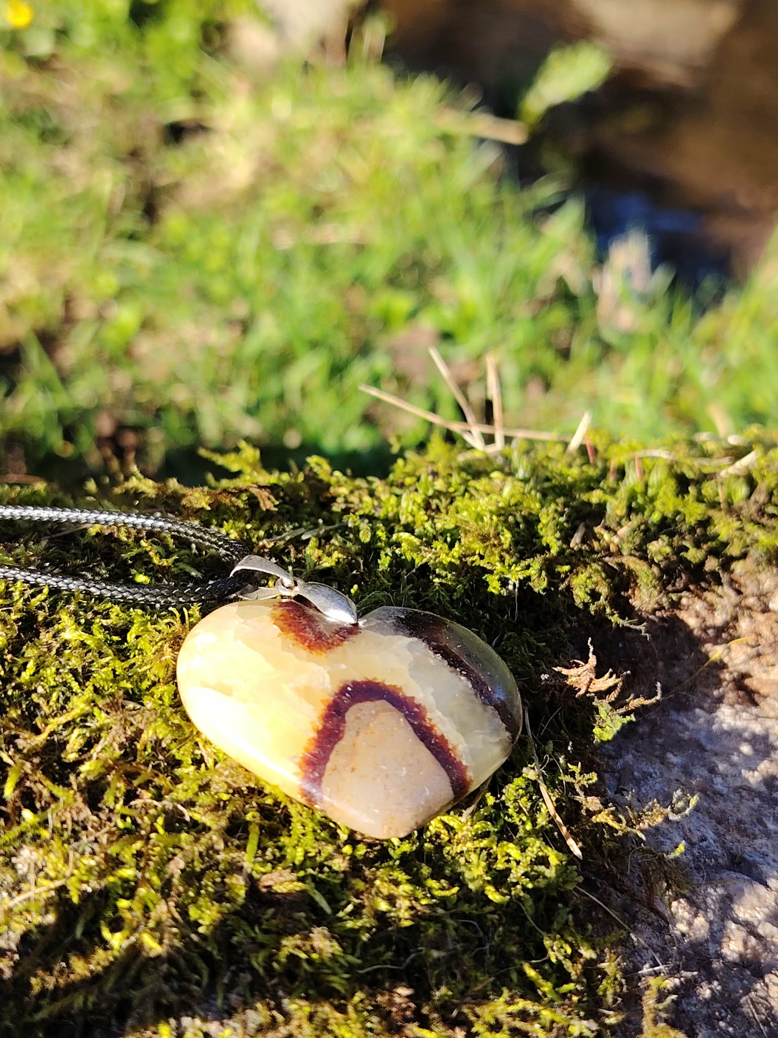 Pendentif cœur en septaria sur mousse en forêt bretonne, dans une lumière naturelle douce, pierre naturelle reliée au calme du mental, à la stabilité et au recentrage.